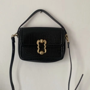 gullig krokodilmönstrad väska  - svart söt liten väska från zara med gulddetaljer, gulddetaljen i fram me ormgrejspännet är slitet 
