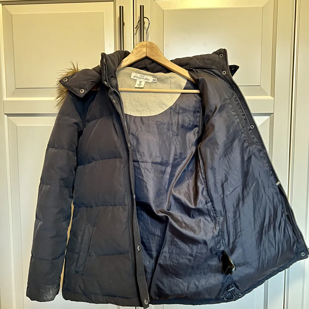 Mycket fin dunjacka från H&M i storlek 36, marinblå med avtagbar päls på huvan. Takit.