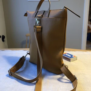 Ryggsäck/Bagpack  - Stilren gul ryggsäck, perfekt till våren!  Aldrig använd därav perfekt skick. Konstläder och fodrad. Rymmer ett A4 block och mer därtill.  Höjd: 36 cm, Bredd: 33 cm, Botten: 8 cm