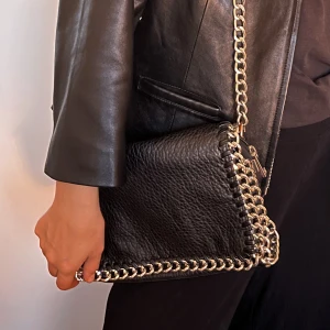 Väska med kedjor - Cool svart väska med långt kedjeband som går att expirementera med.