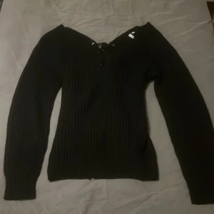Stickad svart tröja - Svart stickad tröja från Nelly, snörning i ryggen och fin uringng vid brösten🖤 Stl Xs men sitter lika bra på S/M, köpt för 345kr och säljs för 150kr inkl frakten🤍