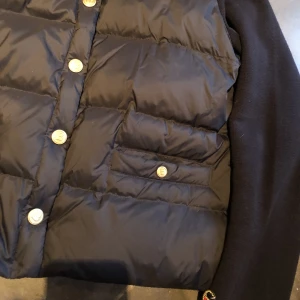 Busnel inella down jacket  - Mörkblå busnel jacka/ kofta med tyg på armarna och ryggen. Endast använd ett par gånger. Köptes för cirka 3500kr