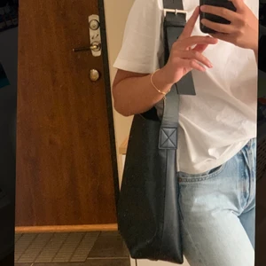 Väska - Svart axelremsväska som inte kommer till användning🐻 Den är köpt på Åhléns och är använd ett fåtal gånger utan att det märks på väskan. Perfekt till skolan då den rymmer både block och dator🥰  