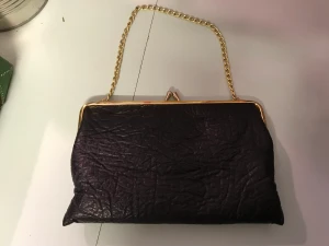 Aftonväska - Vacker svart retro handväska med gammaldags knäppning och guldfärgad länk. Ett fack inuti. Lagom stor. Ren fräsch och hel. 