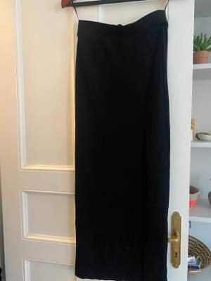 Glittrig svart kjol med slits. Oanvänd med etikett.