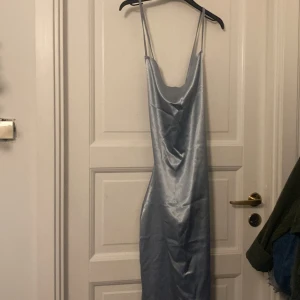 Lång ljusblå klänning  - Fin lång ljusblå klänning som man knyter i ryggen. Har ett snitt så att man kan lätt gå i den. Har aldrig använt den, är i nyskick
