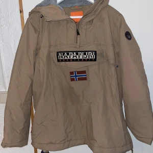 Skidjacka napapijri - Säljer min jättefina skidjacka från  napapijri! Det är en anorak, har ficka på framsidan och dragkedja vid sidan (se bild). Jackan är fodrad så man fryser Inte! använd fåtal gånger men har en fläck som borde försvinna i tvätten. Nypirs är ca 2 300 kr 