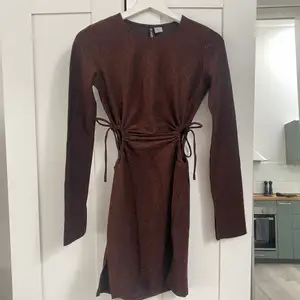 Brun/glittrig klänning med ”cutouts” på sidorna från H&M i storlek XS