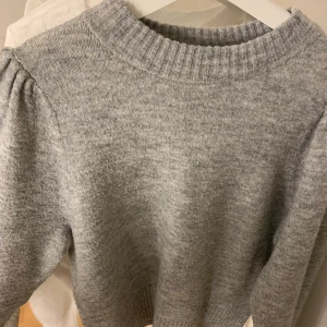 Stickad tröja  - Stickad tröja med volang ärmar, den är använd men i gott skick. 