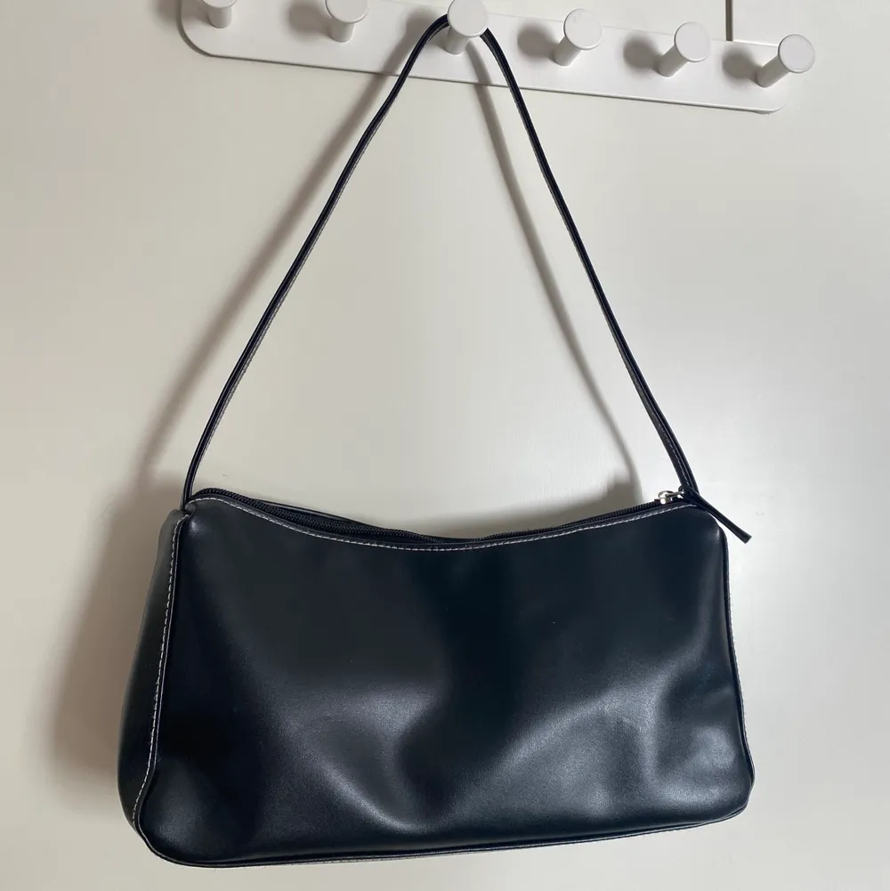 Säljer denna söta svarta skinnhandväska som är dekorerad med vita sömmar🌸. Väskor.