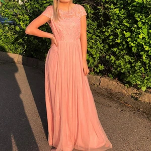 Balklänning - Hej, jag säljer nu min balklänning. Endast använd en gång. Den är en jättefin ljusrosa/smutsrosa färg med spets på överdelen. Den har dragkedja och knappar i ryggen som är jättefint. Perfekt till bal eller bröllop. Jag har oftast Xs och på mig passar den bra då den är i storlek 34. Den var lite lång på mig, även med klackar och jag är 1,57. Den kommer från Vila och kostade från början 800 kr har jag för mig. Köparen står för valfrifrakt och betalar genom swish 🥰