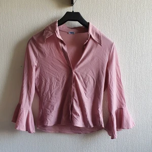 Somrig topp I babyrosa med volangärmar - Somrig topp I babyrosa med 3/4 volangärmar. Åtsittande passform och croppad, perfekt till sommaren. Bra skick inget slitage. Strechig och meshlik ande tyg. Begagnad men aldrig använt själv. 