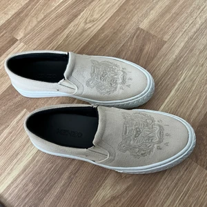 Kenzo skor - Kenzo slip on skor i storlek 36, deras skor är en storlek större så har du storlek 37 som mig så passar 36. Använda max 7 gånger och köpta förra året för Kenzos egna hemsida. Dustbag finns kvar. Säljer eftersom de inte kommer till användning. Skorna är i en beige färg. Pris går att diskuteras.