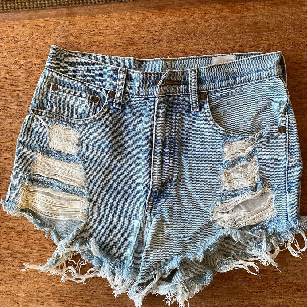 Slitna korta LEVIS jeansshorts i snyggt blekt blå nyans. Jeansstorlek ca 26-27. Vintage. Väl använda därav snyggt slitna. . Shorts.