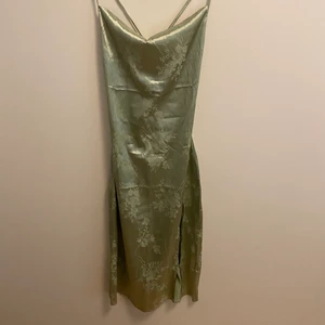 Grön satinklänning - En grön satinklänning med blommigt mönster på som funkar perfekt till fest.