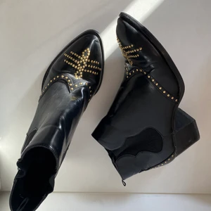 Stövletter med nitar - • Coola svarta stövletter med guld detaljer • Använda, men i bra skick. Flera foton kan skickas ved förfrågan.