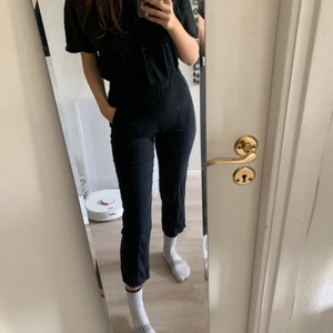 Byxdress svart  - Svart Lululemon byxdress i Stretchigt material. Jätte bekväm och ger snygg passform! Knappar fram och fickor med dragkedja fram på varsin sidan. Fickor bak med knapp. (Jag är 177cm lång)  skriv gärna vid frågor och om pris✨