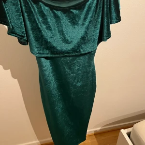 Grön klänning med volanger vid brösten. - Använd ett par gånger men ser helt ny ut.