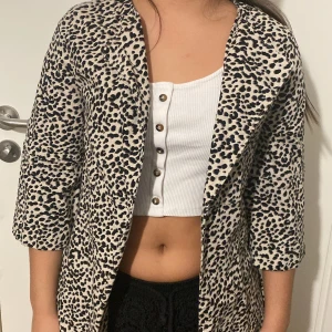 Leopard kofta från H&M - En kofta med leopard mönster som inte kommer till användning. Längd ner till knäna ungefär och det är korta ärmar.