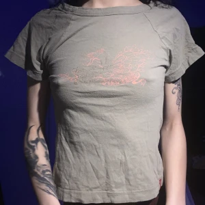 Baby tee från Levis - En grön tröja från Levis, väldigt gammal modell så finns ej längre. Den har så som på andra bilden på båda ärmarna. Väldigt y2k.