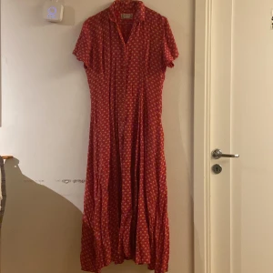 Blommig långklänning  - blommönstrad röd långklänning, med röda knappar, 100% viscose, bra skick