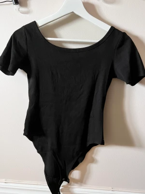 Svart body - Svart body i storleken S med djup urringning och halvt öppen rygg. Säljer pga för mycket kläder. Sitter super fint! Helt oanvänd 