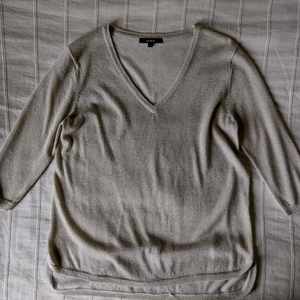 Beige tunnare stickad v-ringad tröja med guldskimmer, storlek S - En tunnare stickad tröja. Fin beige färg med guldskimmer. V-ringad, loose och lite längre baktill. Storlek S. 75% viskos och 25% lurex. Bara använd någon enstaka gång. 