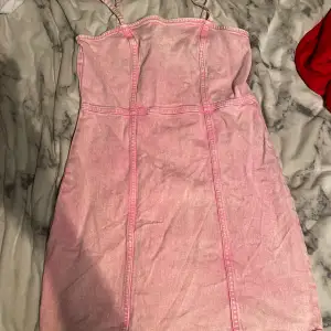 En rosa jeansklänning med dragkedja på ryggen för att få av/på klänningen. Jag är 162cm och klänningen slutar en bit ovanför knäna