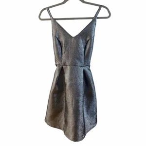 Metallig silvrig klänning - Klänning i skinande slirig/grå färg. Bra skick. Kjol ”går ut” lite när den är på. Strl S.