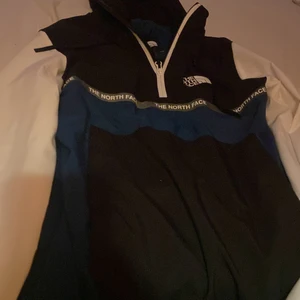 The north face jacka - En snygg vindjacka med luva från the north face. Den är en mörkare färg av blågrön med svart och vitt. Jackan e praktiskt taget helt ny och är använd 1,2 ggr! Jackan är i xs men skulle säga att den är ganska så stor i modellen.(köpare står för frakt) 
