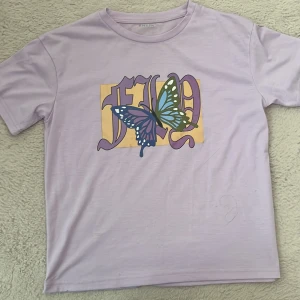 Lila t-shirt - Ljus lila t-skirt med en fjäril på.