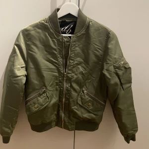DBrand bomberjacka - I bra skick då jag knappt använt den. Olivgrön och orange på insidan. Guld detaljer. 