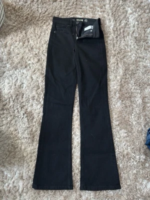 Svarta bootcut jeans med hög midja - Snygga svarta bootcut jeans med hög midja. Jeansen har utsvängda ben och stängs med dragkedja och knapp. Perfekta för en trendig och avslappnad stil. Materialet är stretchigt för extra komfort.💗