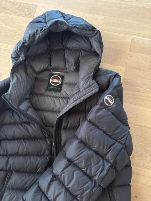 Colmar jacka - Säljer en svart dunjacka från Colmar med huva och dragkedja. Jackan har quiltad design, två sidofickor med dragkedja och Colmar-logga på ärmen. Perfekt för kalla vinterdagar och riktigt skön att bära. Storlek M, pris kan diskuteras 