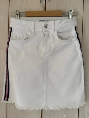 Vit denimkjol från Zara  - Vit jeanskjol från Zara med blå och röda revärer. Fransig nertill. Obetydligt använd.