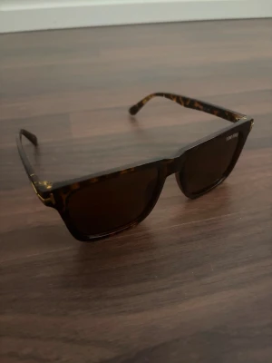Tom Ford solglasögon  - Kostar 4 tusen online, Snygga solglasögon från Tom Ford med klassisk fyrkantig form och brunmelerat, tommigt mönster på bågarna. Glasen är mörka och ramen har en exklusiv känsla. Perfekta för dig som vill ha en stilren accessoar med lyxig touch.