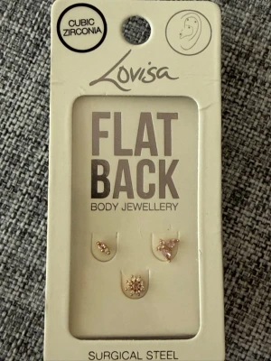 Lovisa örhängen med cubic zirconia - Säljer ett set med tre små örhängen från Lovisa i kirurgiskt stål med cubic zirconia. Örhängena har flat back och olika former, dekorerade med gnistrande stenar rosa i guldton. 