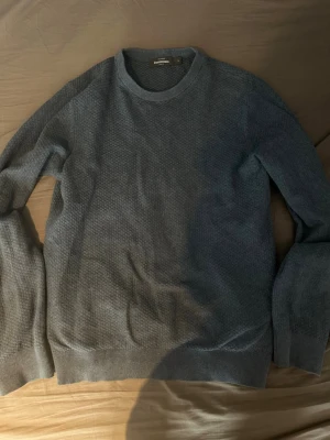 Mörkblå stickad tröja Dressmann - Mörkblå stickad tröja från Dressmann i storlek S. Tröjan har rund halsringning, diskret strukturmönster och ribbade muddar vid ärmslut och nederkant. Perfekt för lager på lager och enkel att matcha med olika outfits.