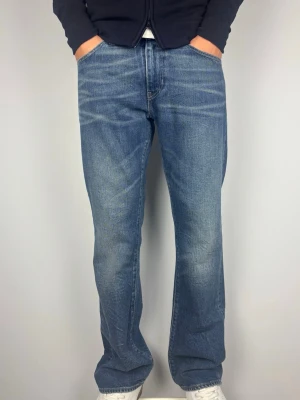 Bootcut Levis 527 Vintage Jeans - Levi's 527 vintage bootcut jeans. Snygga fades framtill som ger jeansen extra karaktär och en snygg bootcut passform. Färg: Blå med snygga fades framtill Passform: Bootcut Storlek: W34 L32 Skick: A-B Grade Mått (±1 cm): A: 43 cm B: 107 cm C: 23 cm D: 30 cm Passar bra på modellen på bilden som är 189 cm lång och väger 82 kg. Tveka inte att höra av dig vid frågor eller funderingar. Skickas snabbt!