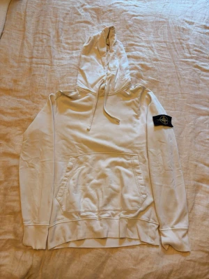 Stone Island Hoodie - Stone Island hoodie – vit 🤍  Klassisk vit Stone Island hoodie med det ikoniska Compass-märket på vänster ärm.  Clean modell som passar till både jeans och cargo/byxor och fungerar året runt.  Har slitningar i ändarna på ärmarna, vilket syns på bilderna. I övrigt bra begagnat skick.  Säljs därför till ett lägre pris.