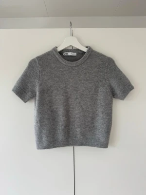 Stickad t-shirt från Zara - Säljer denna fina grå stickade T-shirt från Zara.  Tröjan är använd en gång och är därför i väldigt fint skick, inga tecken på användning.💕