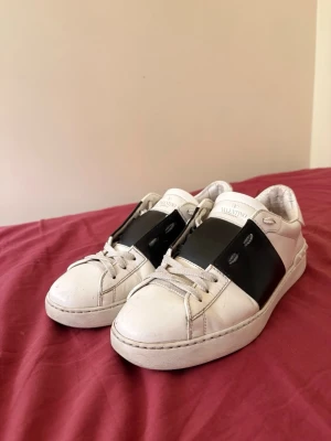 Valentino vita sneakers med svart detalj - Snygga vita sneakers från Valentino. Skorna har låg profil. Perfekta för dig som vill ha en stilren look.   Storlek 40 men passar perfekt till 39. Priset kan diskuteras 