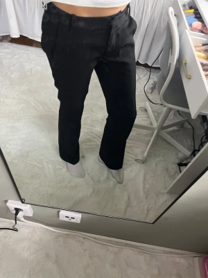 Bikbok kostym byxor - Säljer ett par svarta kostymbyxor med rak passform och låg midja. Byxorna har bälteshällor och diskreta fickor. Perfekta för en clean och stilren look. Materialet ser ut att vara en klassisk kostymblandning som ger en snygg siluett.