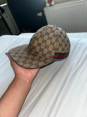 Beige gucci keps canvas - Äkta Gucci keps, gamla modellen, köpt 2020, finns Gucci chip i den men ofungerande då den är gammal OBS den har nån gång ramlat ur men finns bild med den som ni ser på annonsen, inga andra tillbehör kvar, har digital kvitto från säljaren som jag köpte ifrån här på Plick.