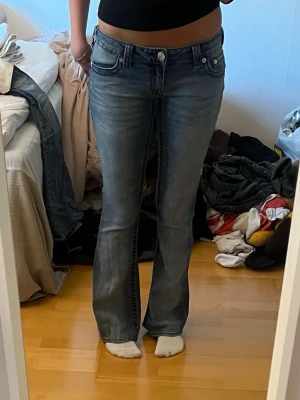True religion jeans med röda detaljer  - Säljer ett par true religion jeans med låg midja.                Är själv 165 cm å jeansen är lite för långa för mig så därför är dom lite utnötta längst ner men inget man tänker på.                                                                 Storlek 25