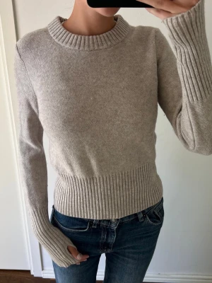 Beige stickad tröja med tumhål - Ooootrolig stickad tröja från COS i nyskick! Endast använd ett fåtal gånger. Hål för tummarna   OBS! Har endast möjlighet att sälja tröjan under en kort period