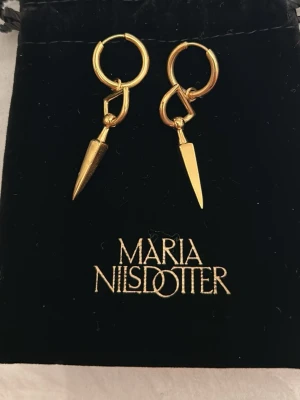 Maria Nilsdotter Bitten örhängen guld - Säljer ett par ikoniska Bitten örhängen från Maria Nilsdotter i guldpläterat silver. Örhängena har en unik, spetsig design som ger en edgy vibe och är perfekta för dig som vill sticka ut. Kommer i originalpåse. Nästan som nya!