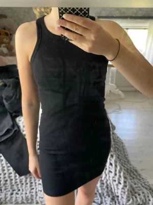 Svart ribbad klänning - Säljer en svart, ribbad klänning från NA-KD. Klänningen är ärmlös med rund halsringning och har en tight, kroppsnära passform. Aldrig använd. 
