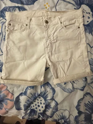 Vita midwaist shorts med fickor - Snygga vita shorts med upprullade benslut och klassisk femficksdesign. Shortsen har knapp och dragkedja framtill samt diskreta sömmar på bakfickan. Perfekta för varma dagar och enkla att matcha med allt.