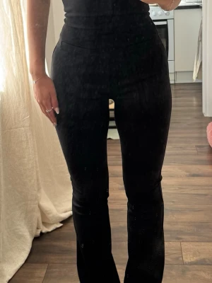 Svarta leggings med utsvängda ben - Säljer en svart, tight jumpsuit och utsvängda ben. Modellen halterneck och öppen rygg. Materialet ser stretchigt